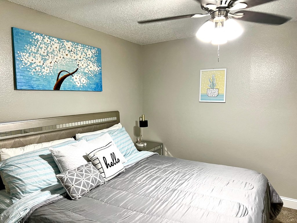 our bedroom has a large bed and a ceiling fan