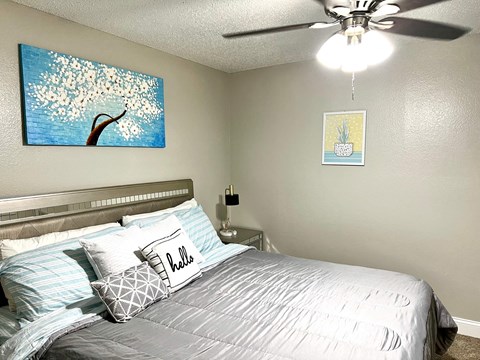 our bedroom has a large bed and a ceiling fan