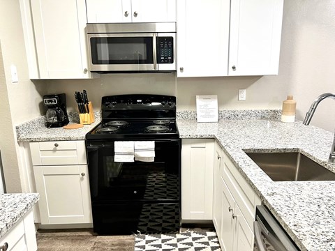a kitchen with white cabinets and a black stove and microwave