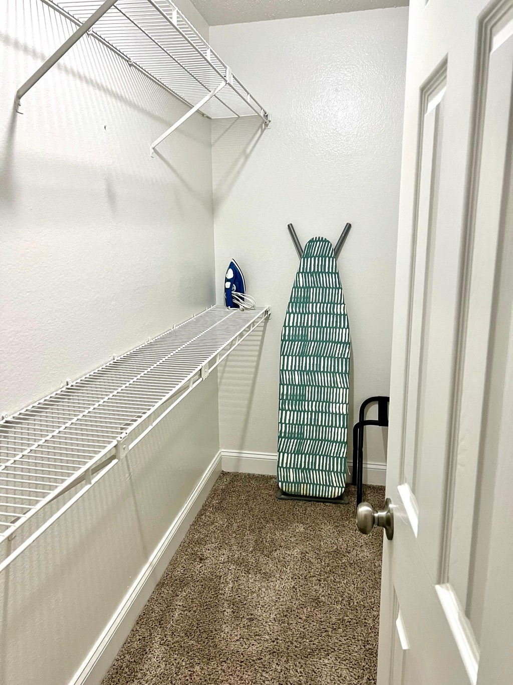 a walk in closet with an open door and a suitcase on the floor