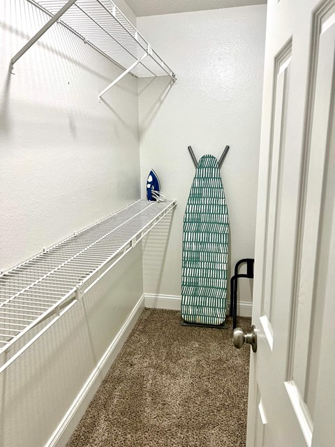 a walk in closet with an open door and a suitcase on the floor