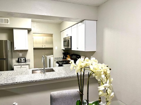 a kitchen with white cabinets and a vase with flowers