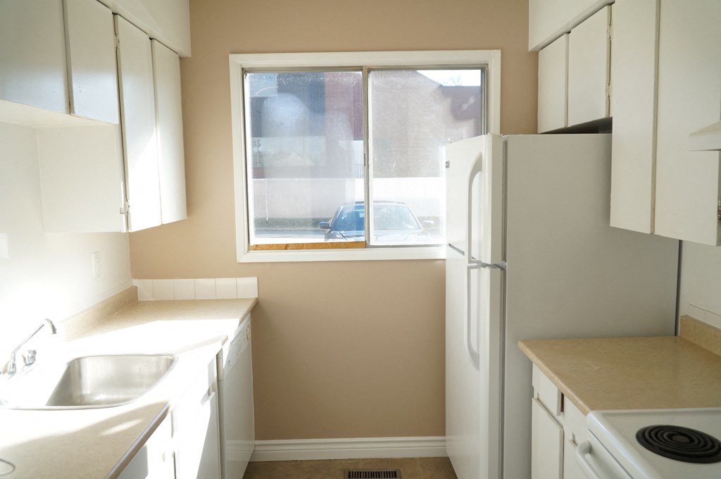 a small kitchen with white appliances and a window