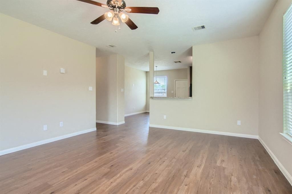 an empty living room with wood floors and a ceiling fan