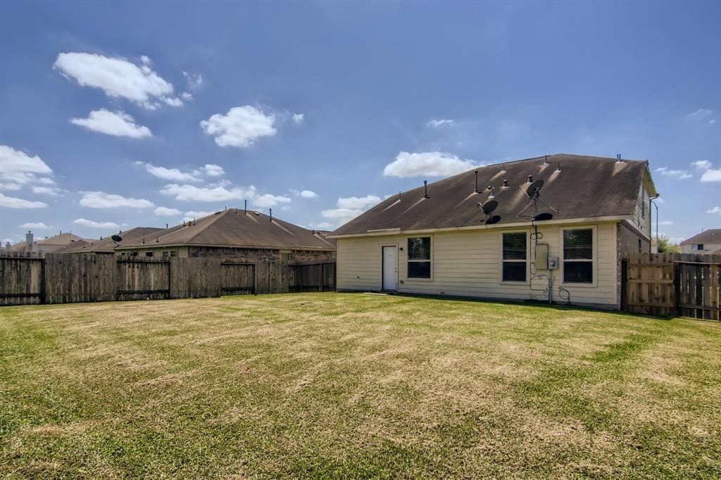 a backyard with a white house and a wooden fence