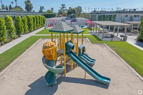 A playground with a yellow and green slide and a green and yellow structure.