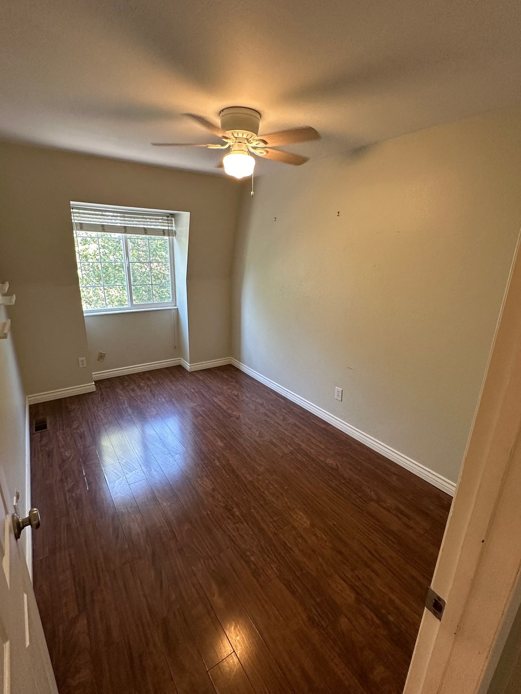 an empty living room with wood floors and a ceiling fan