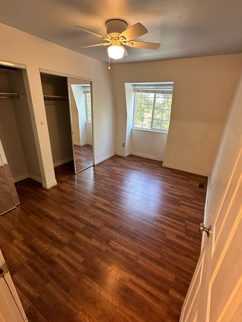 an empty living room with wooden floors and a ceiling fan