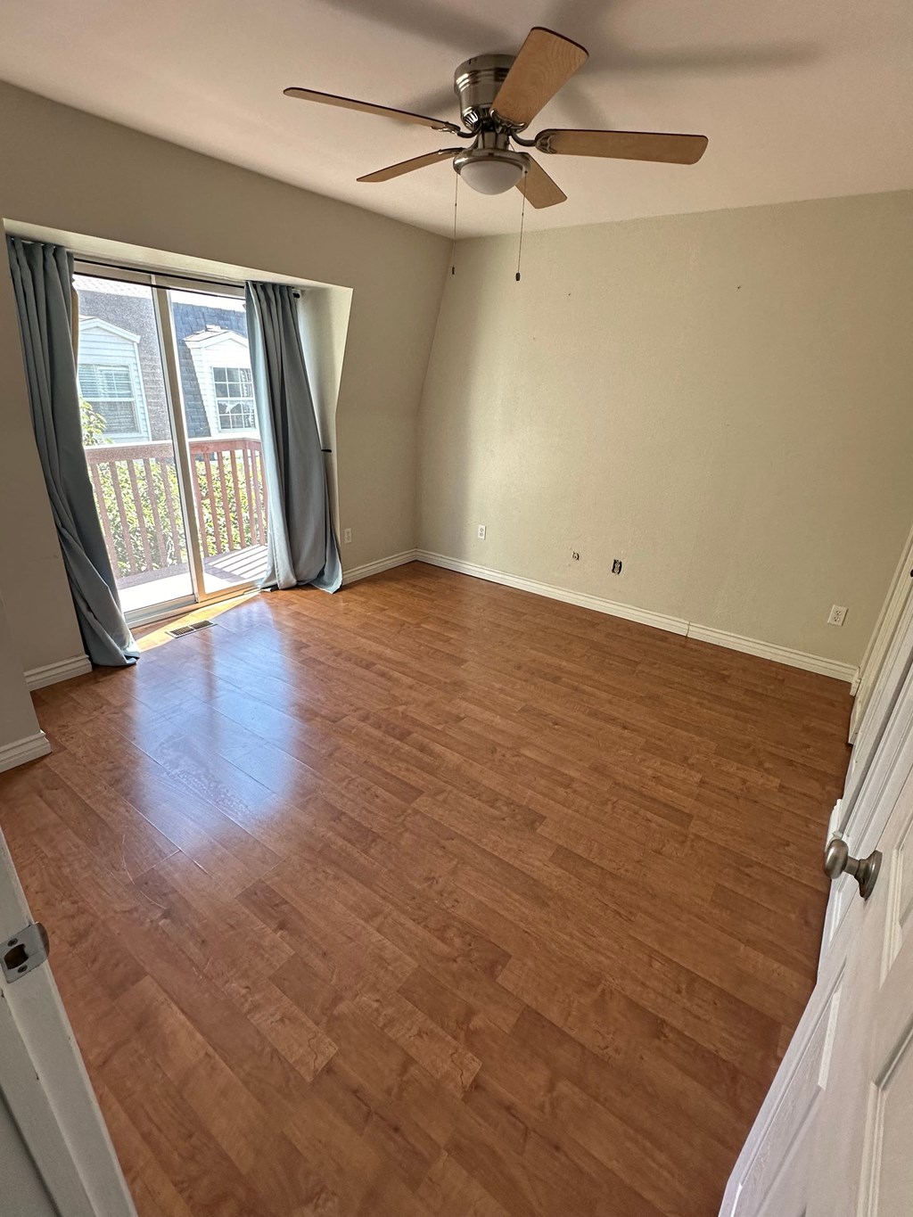 an empty living room with wood flooring and a ceiling fan