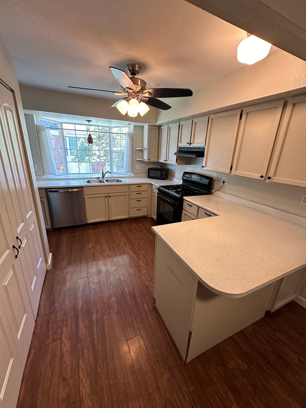an empty kitchen with white cabinets and a ceiling fan