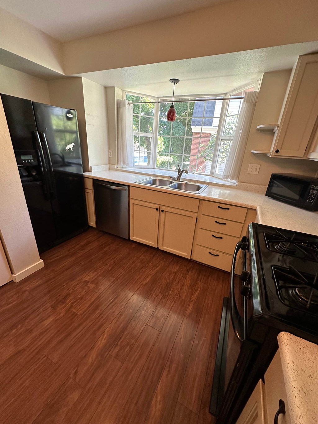 an empty kitchen with wooden floors and a window