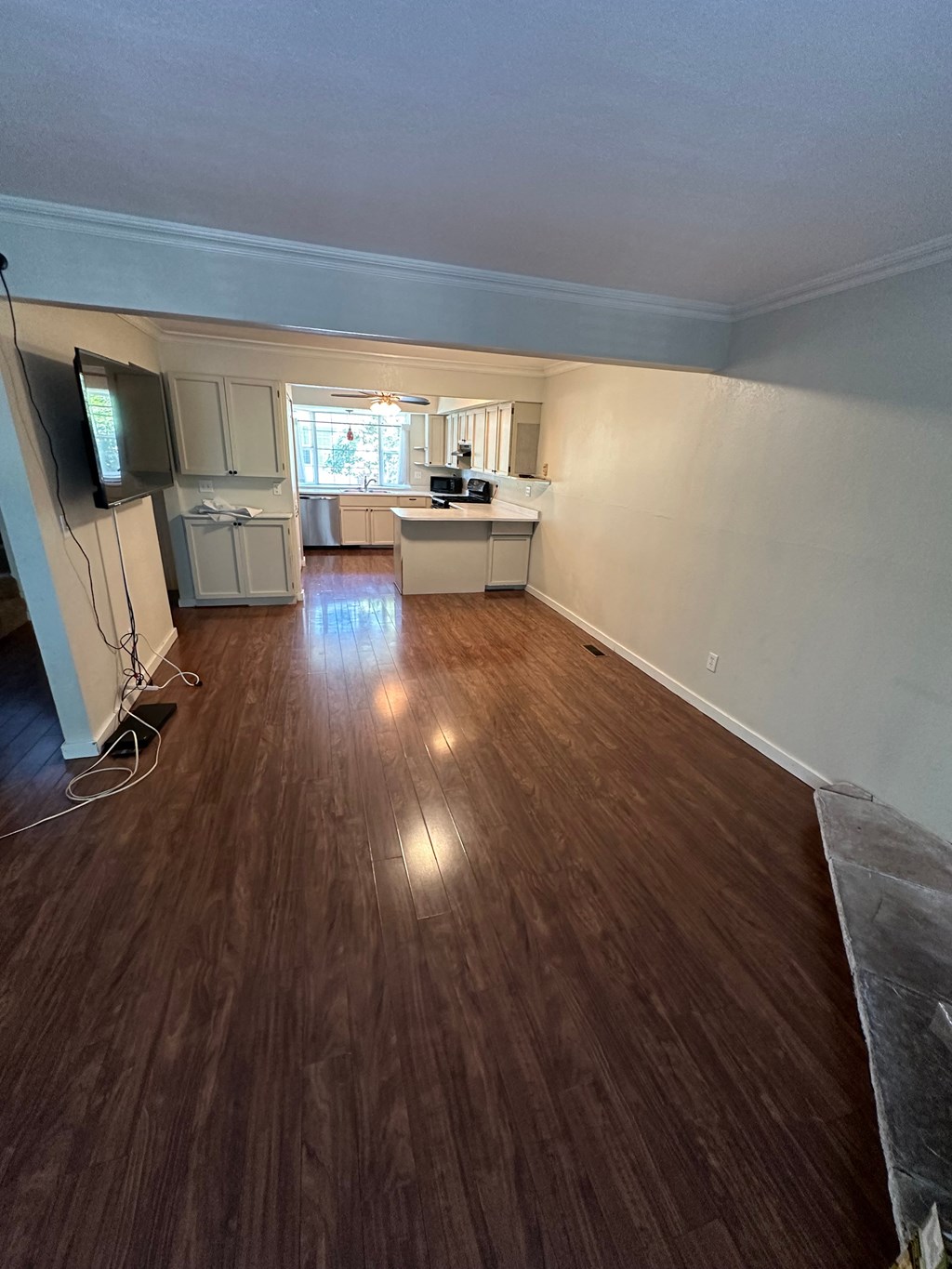 an empty living room with wooden floors and a kitchen