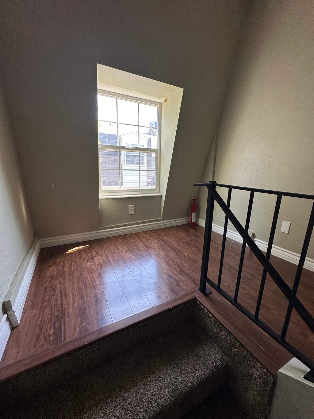 a room with a staircase and a window and wood flooring