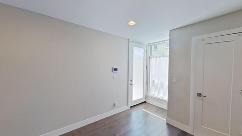 a living room with white walls and a door to a balcony