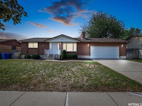 the front of a brick house with a yard and a white garage door