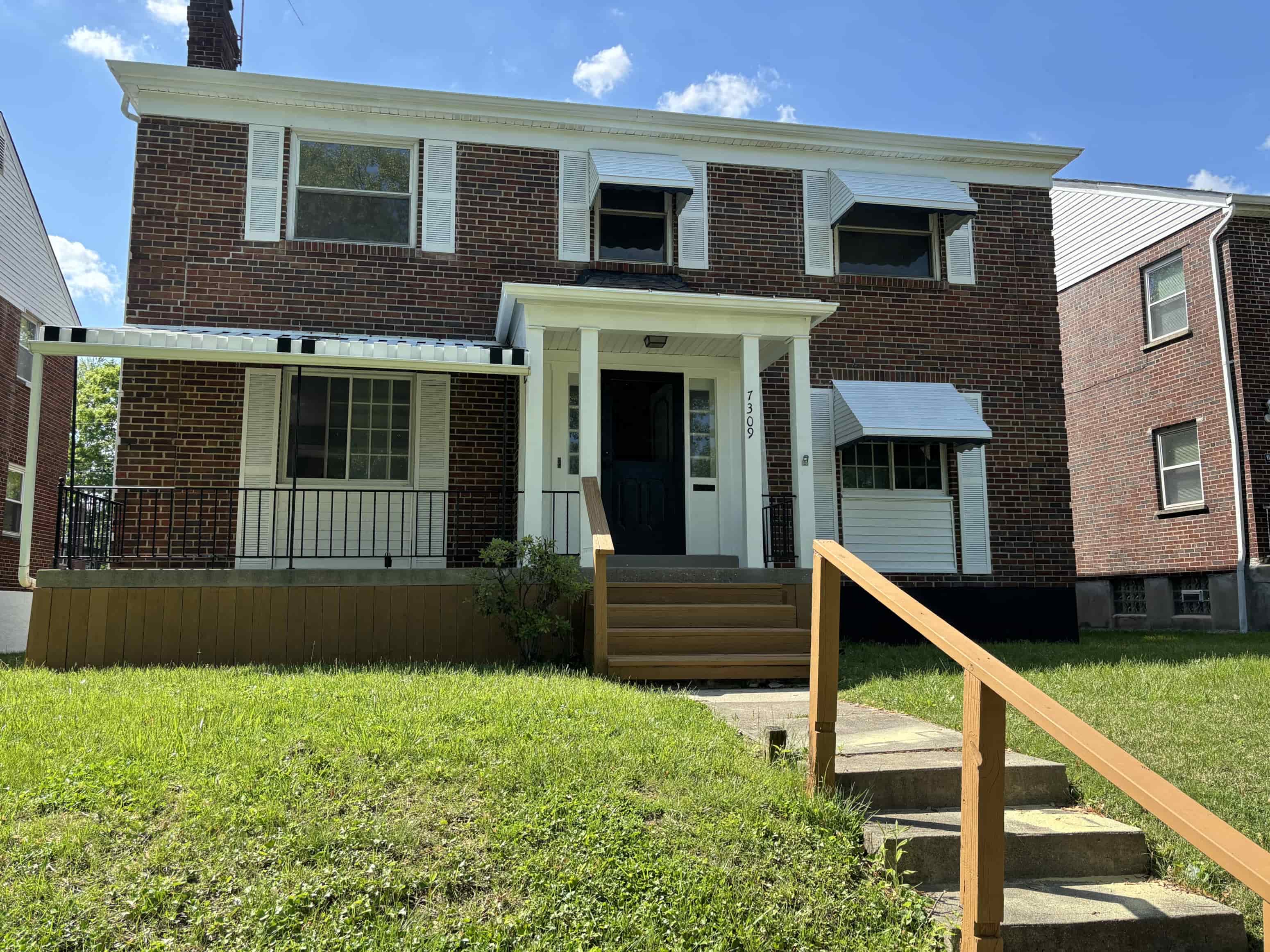 the front of a brick house with a porch and stairs