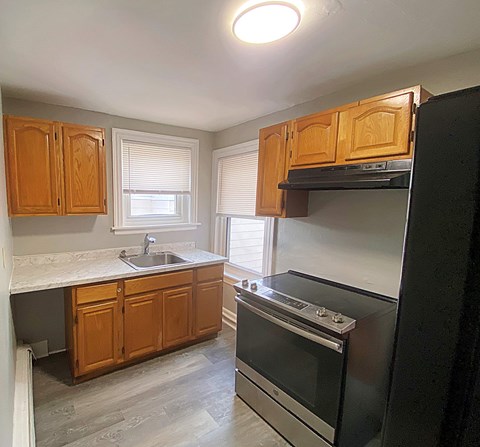 A kitchen with wooden cabinets and a black oven.