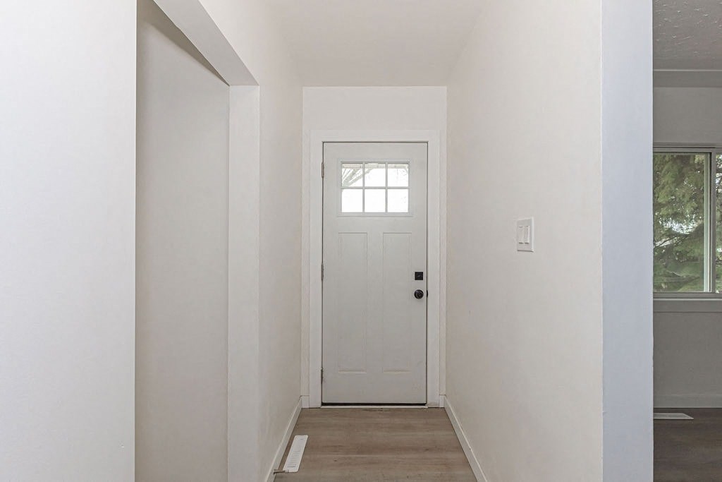 an empty hallway with a white door and a window