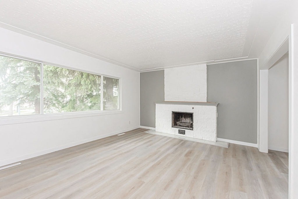 an empty living room with a fireplace and a window