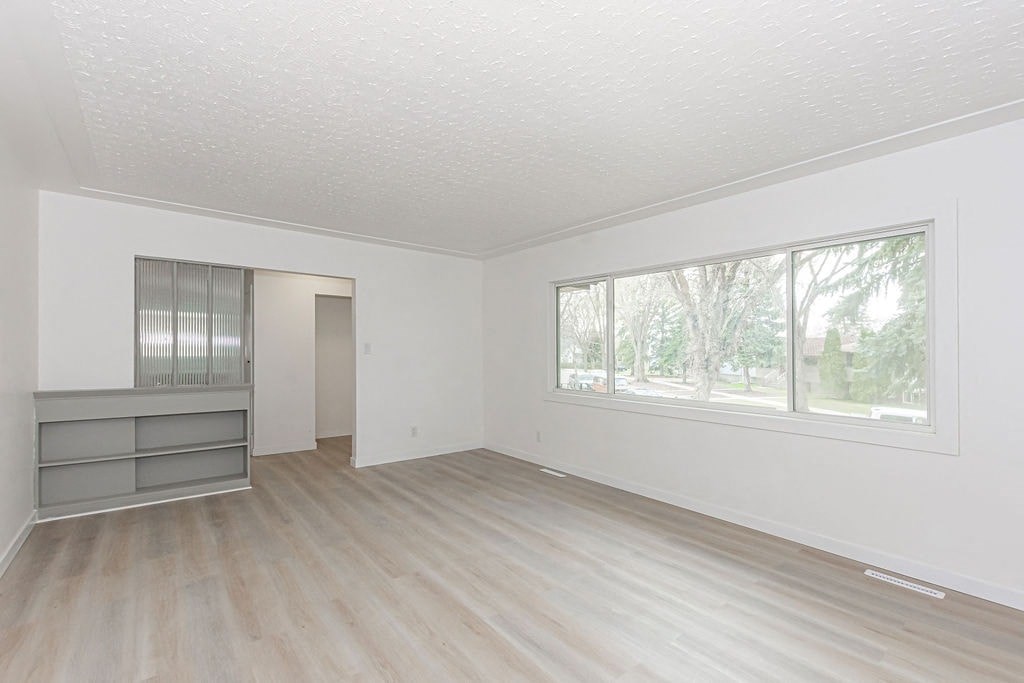 an empty living room with a large window and wooden floors