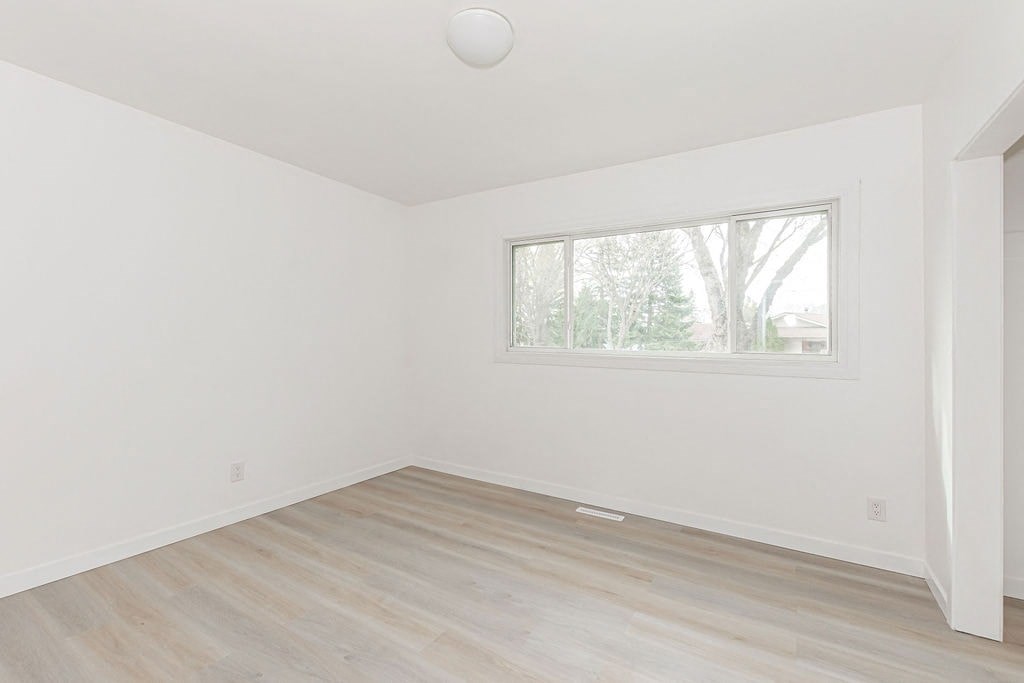 an empty room with a window and wooden floors