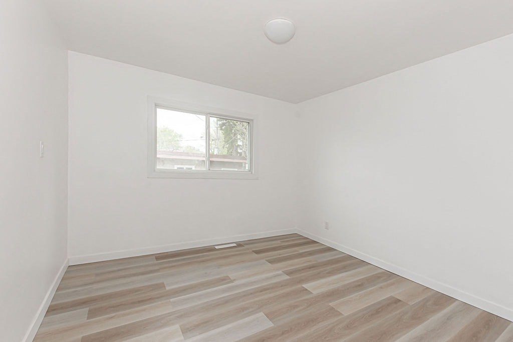 an empty room with a window and wooden floors