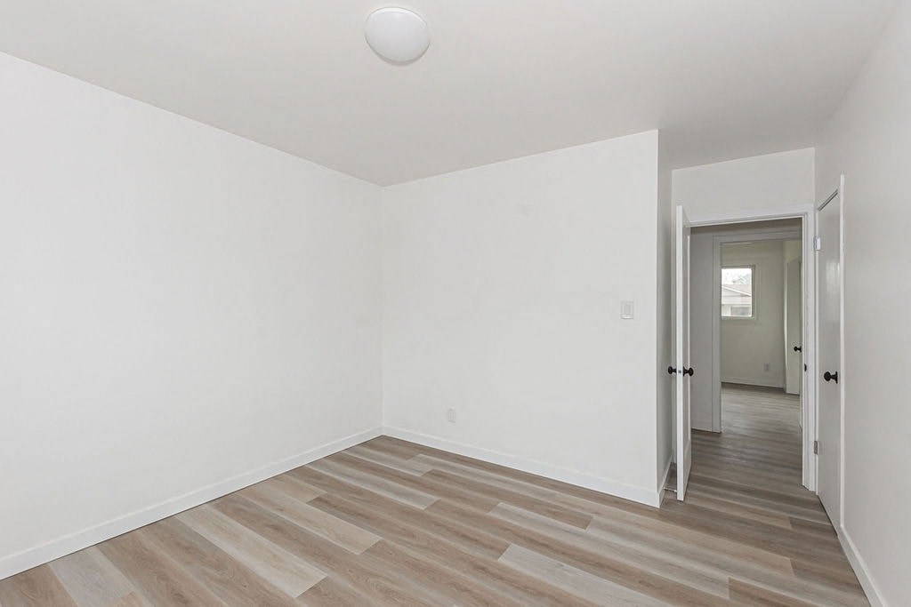 an empty room with white walls and wood floors