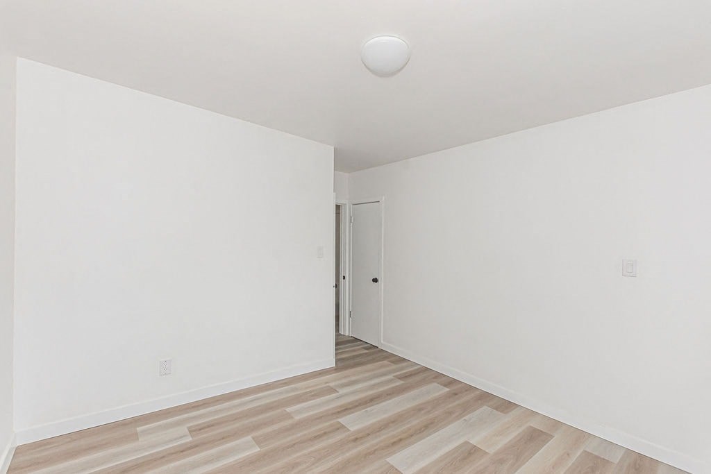 an empty room with white walls and wood floors