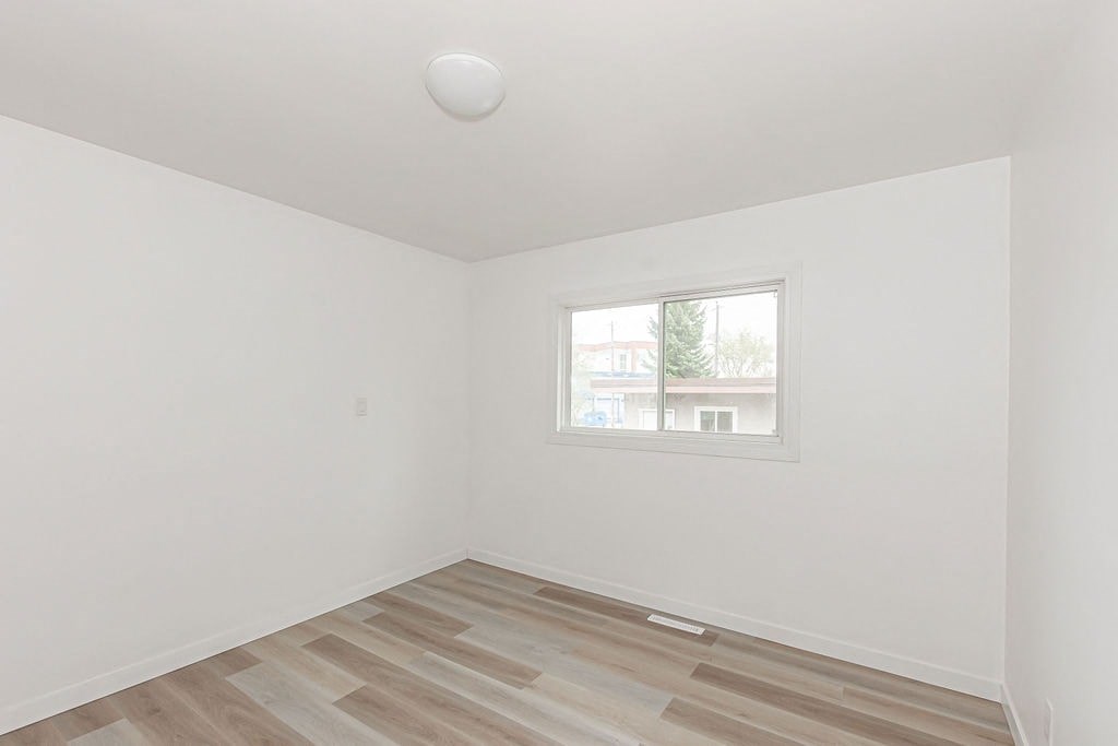 an empty room with a window and wooden floors