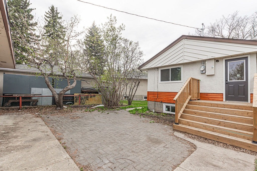 a small house with a brick driveway and a deck