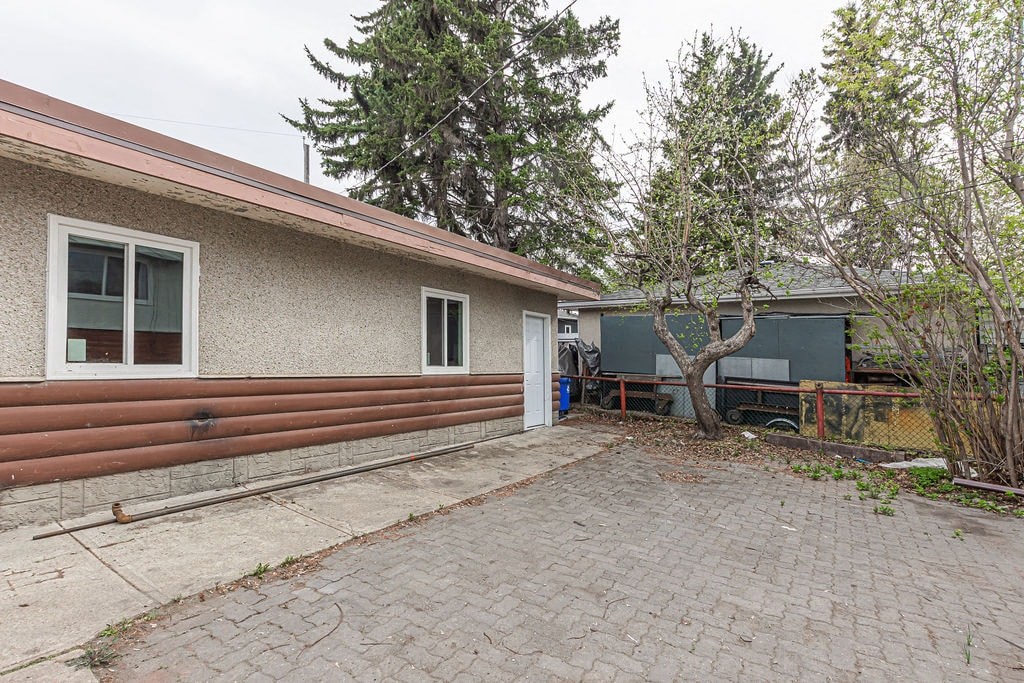 the back yard of a house with a brick patio and a tree