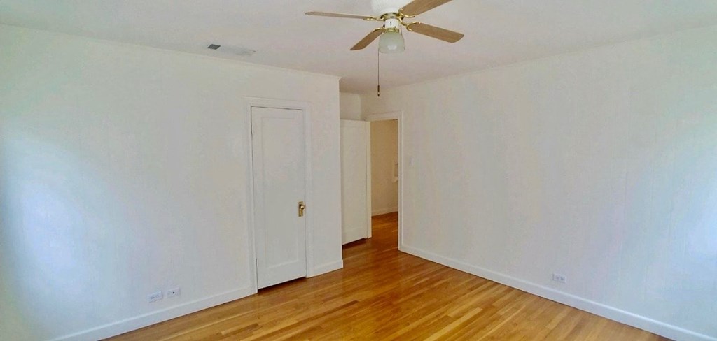 an empty room with a ceiling fan and wood floors