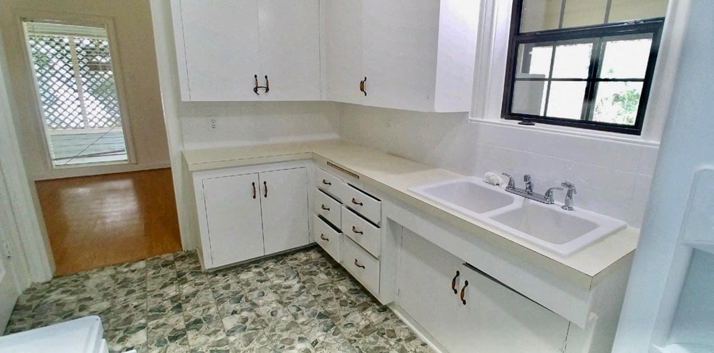 a kitchen with white cabinets and a sink and a window