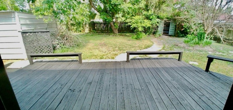 a deck with two benches and a yard in the background
