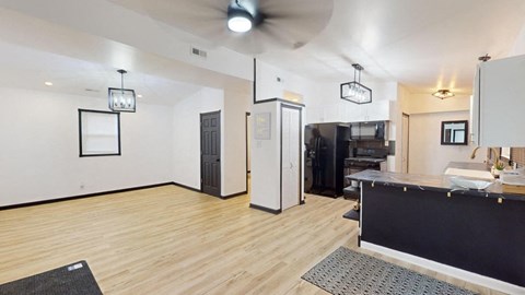 the living room and kitchen of a house with wood floors and white walls