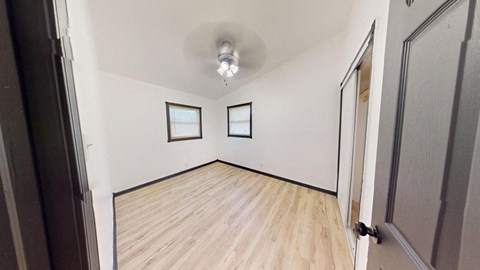 an empty living room with a hardwood floor and a ceiling fan