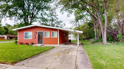 a small red house with a driveway in front of it