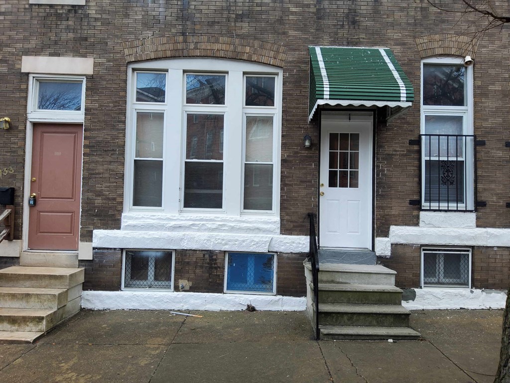 the front of a brick house with a white door and windows