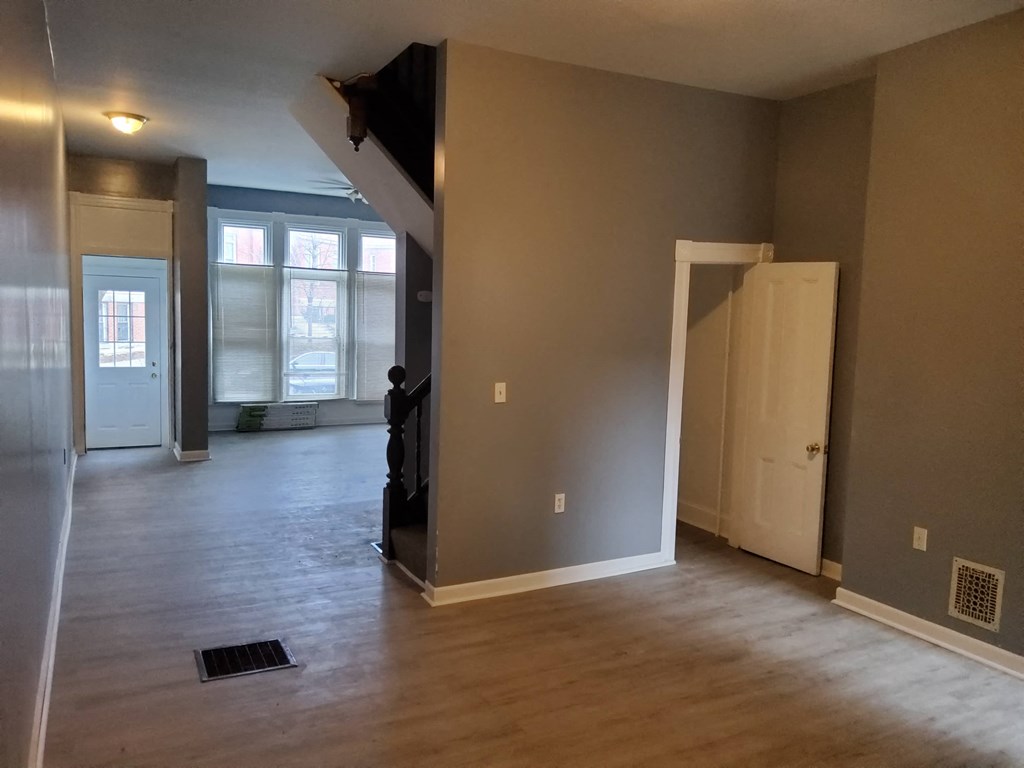 an empty living room with a hard wood floor and a staircase