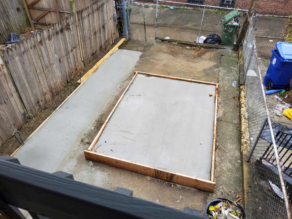 a concrete floor in a backyard with a chicken coop