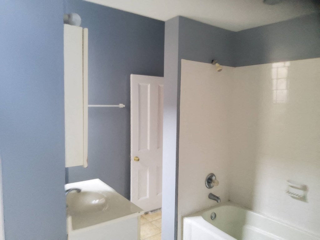 a bathroom with blue walls and a white sink and tub