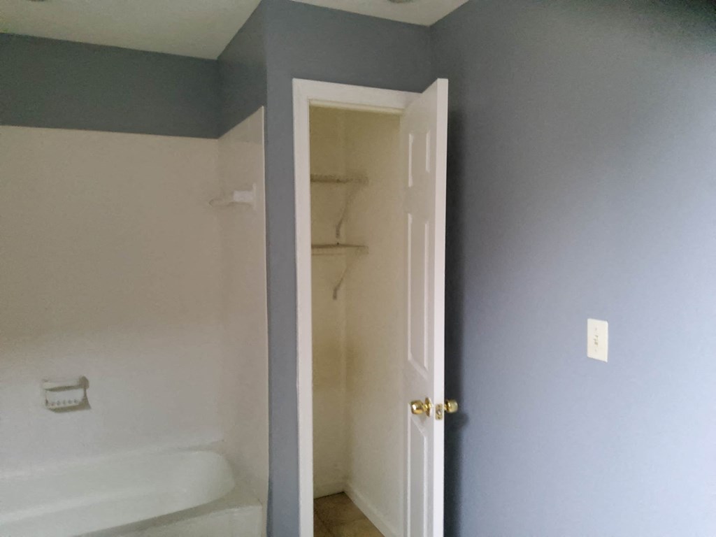 the bathroom door is open to a white tub and a blue wall with a closet