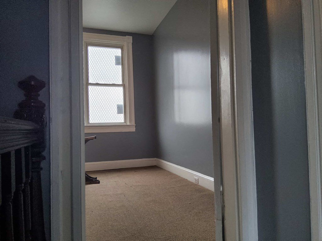 a small room with a window and a carpet