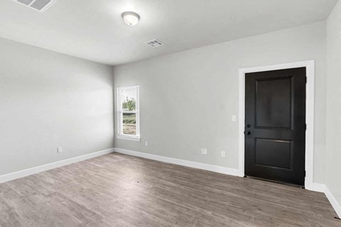 an empty living room with white walls and a black door
