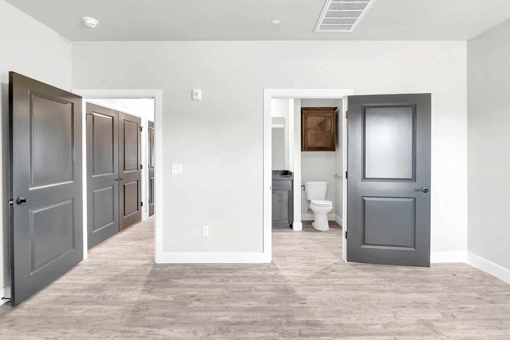 a long hallway with doors and a toilet in a room