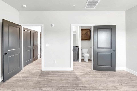 a long hallway with doors and a toilet in a room