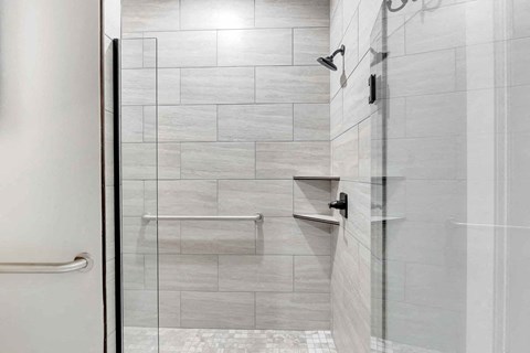 a white tiled bathroom with a glass shower door