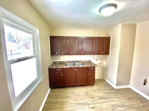 a small kitchen with wooden cabinets and a window