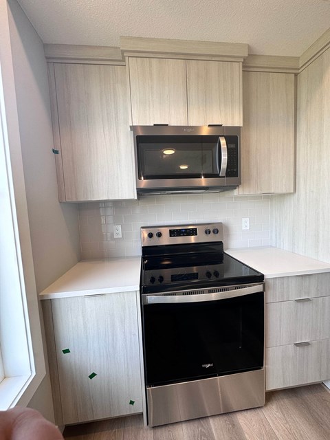 a kitchen with white cabinets and a stove and microwave