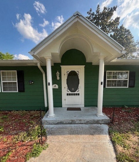 a green house with a white door and a porch